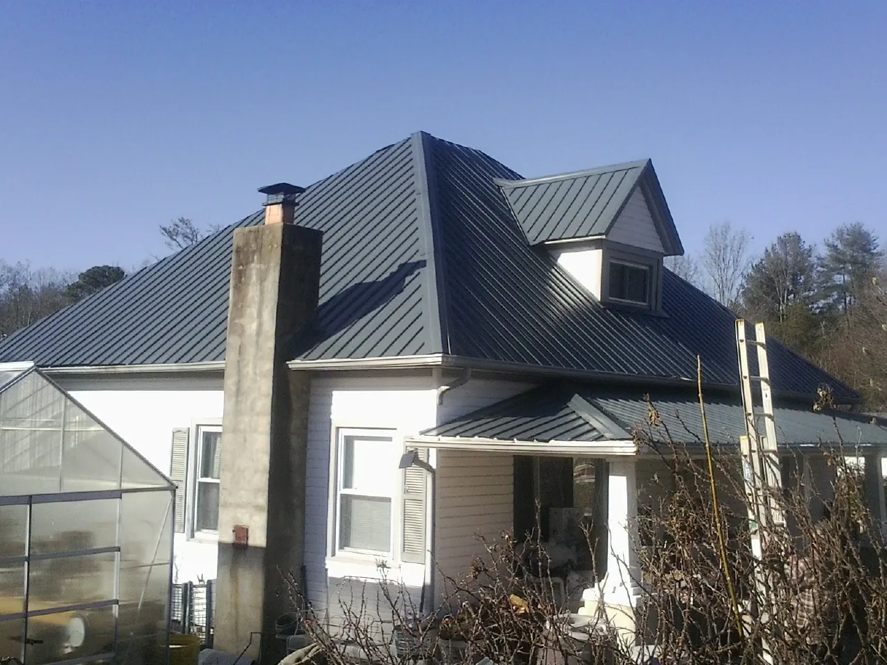 Dark blue standing seam metal roof on a white farmhouse with dormer — Slate & Tile Roof Repair by Roofing Brothers in Woosung