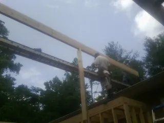 Carpenter setting a ridge beam over a new addition frame — Ice Dam Removal by Roofing Brothers in Woosung