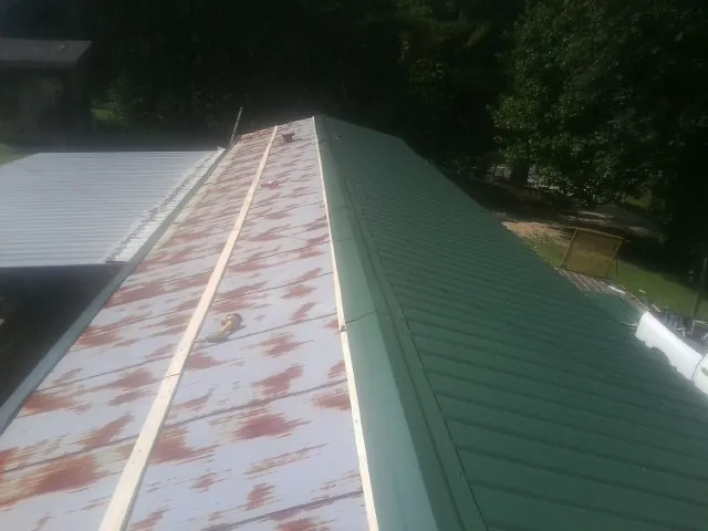 Old rusted panels beside newly installed green metal roofing — Wind Damage Roof Repair by Roofing Brothers in Woosung