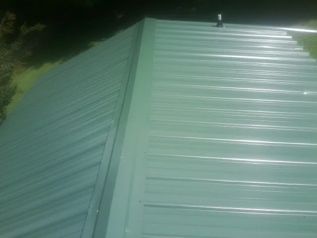 New green metal panels meeting at the ridge of a roof — Flat Roof Repair work by our crew in Woosung