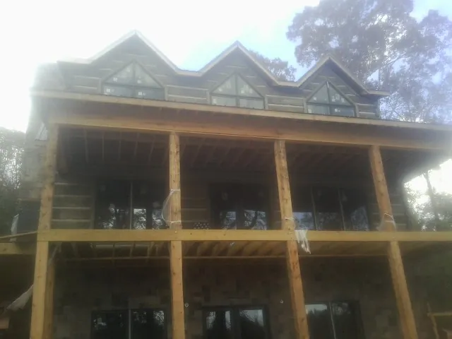 Dormers and porch framing on a large log home under construction — Roof Coating work by our crew in Woosung
