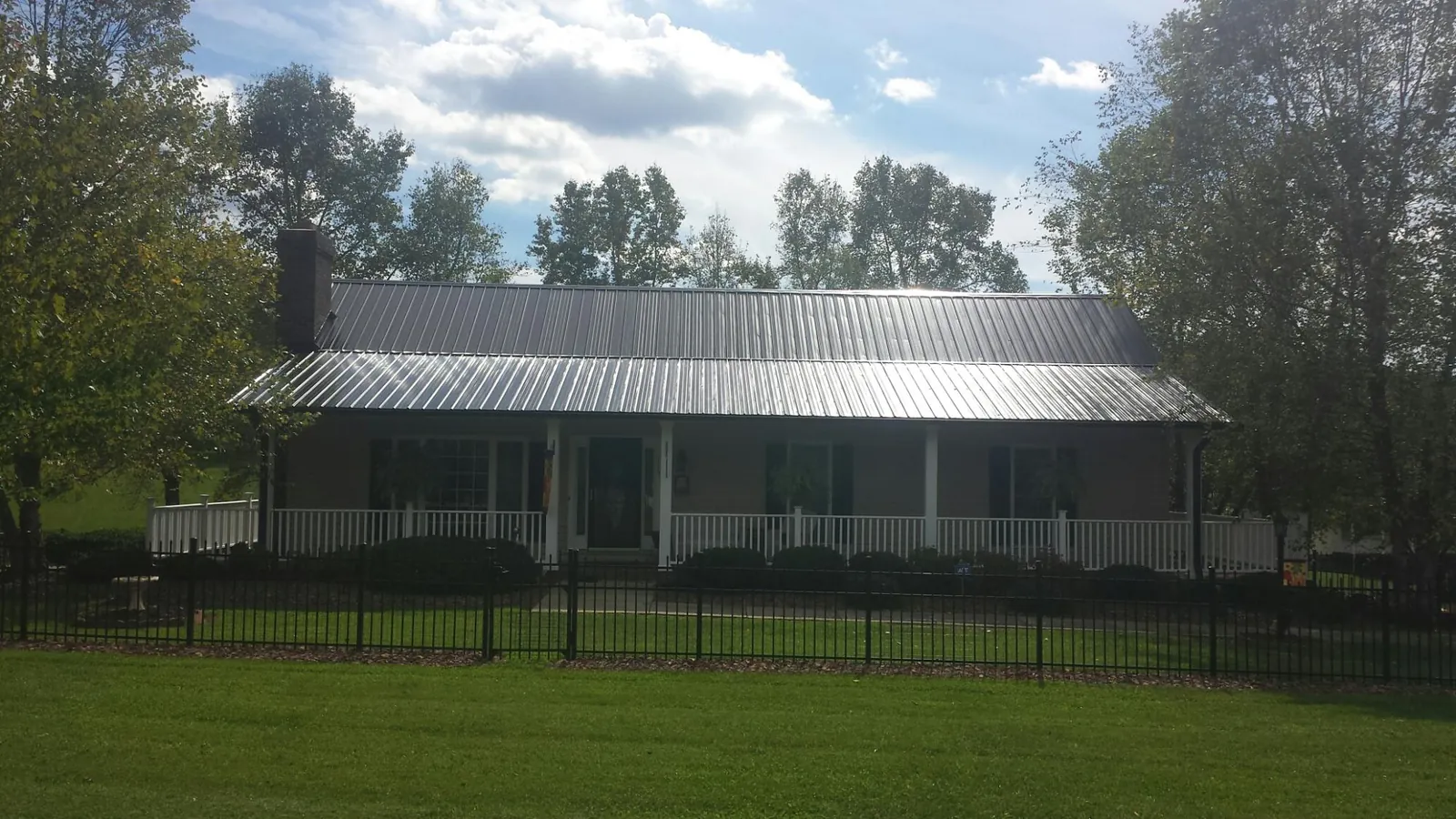 Gray metal roof on a brick ranch with a full width front porch — Gutter Guard Installation work by our crew in Woosung