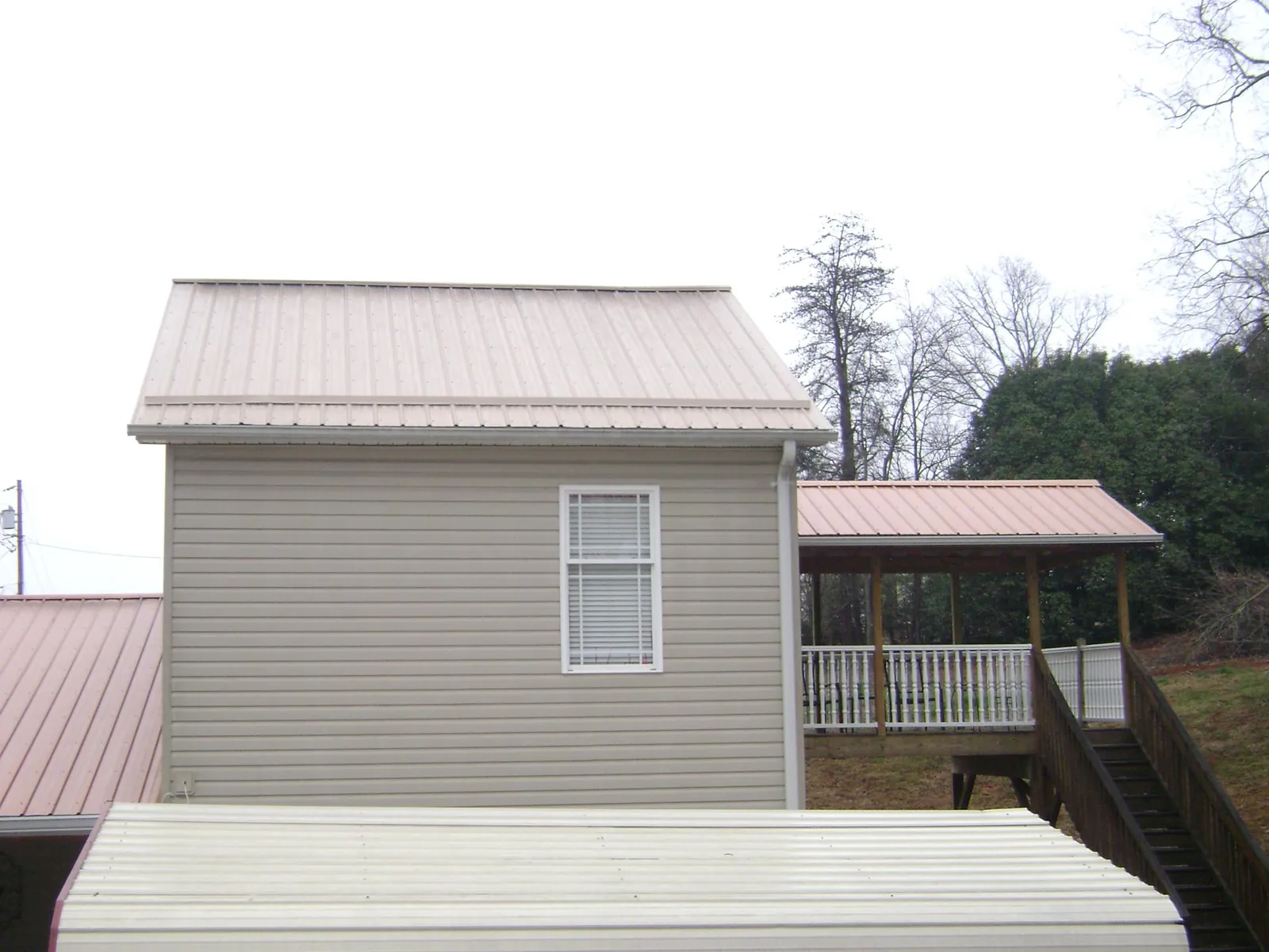 Tan metal roofs on a two story addition and attached porch, from a Roof Replacement job in Woosung